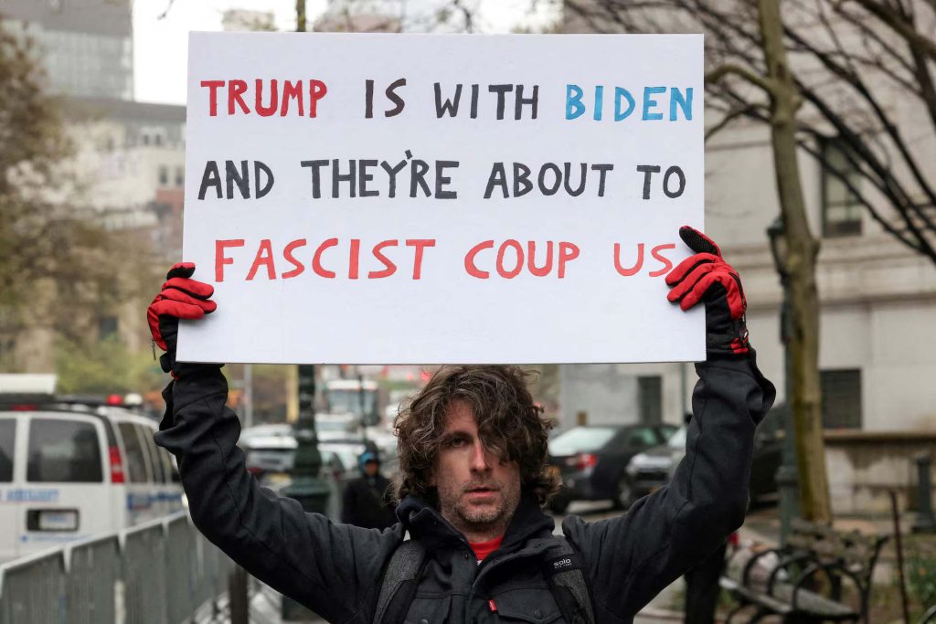 Max Azzarello of St. Augustine, Florida, who police identified as the man who set himself on fire on Friday, April 19, 2024, outside the New York courthouse where Donald Trump's historic hush-money trial was taking place, holds a sign while protesting outside the Manhattan criminal courthouse in New York City, New York, U.S., April 18, 2024. | Caitlin Ochs